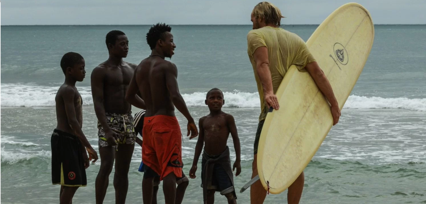 Still image African Territory surfer at the beach with locals